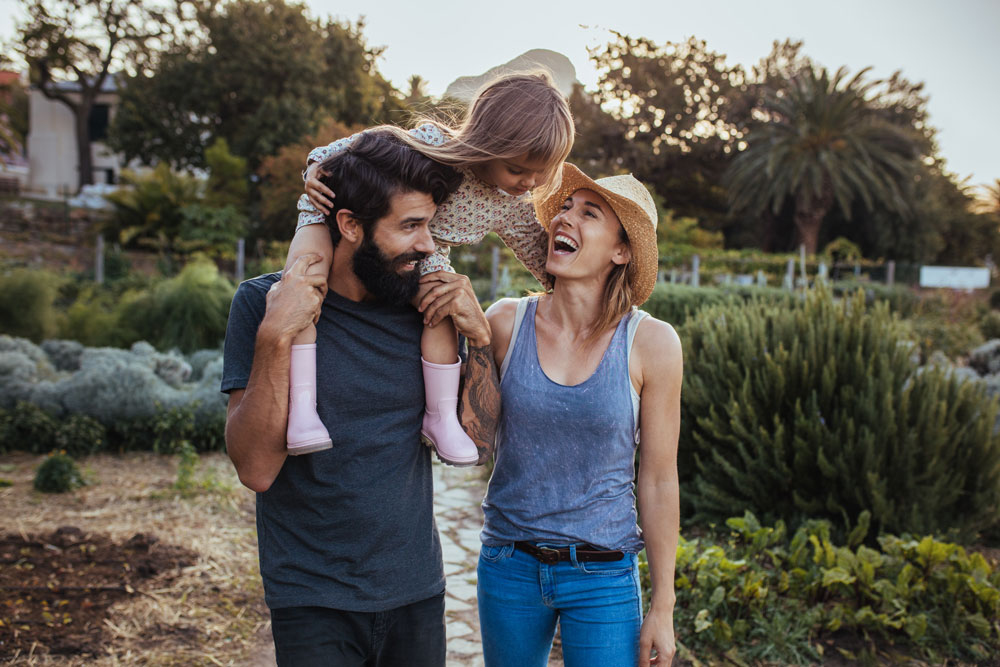 Happy young family of three walking through a garden.