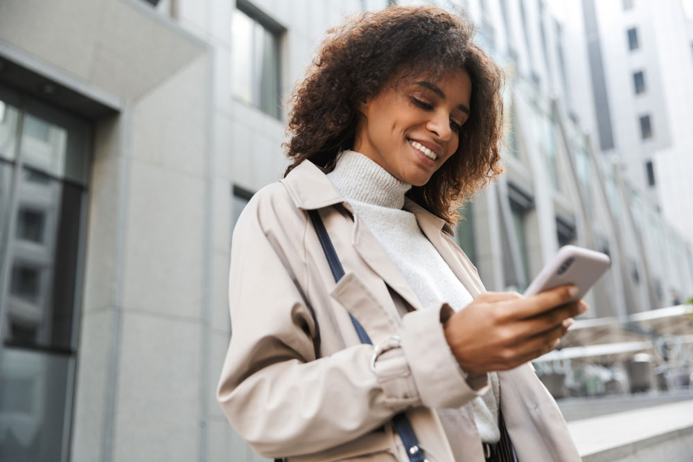 Young business professional smiling at their phone.