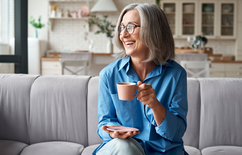 Woman looking comfortable holding tea cup in living room.