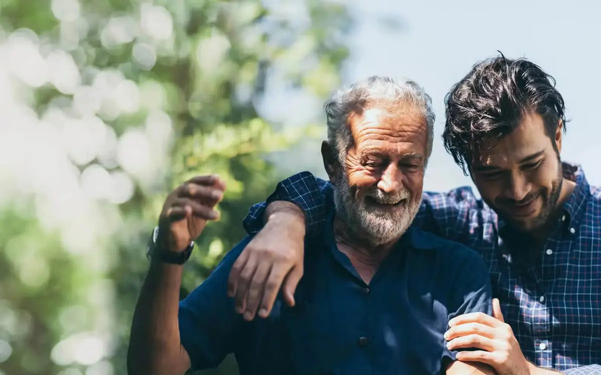 A happy elderly man embracing his son